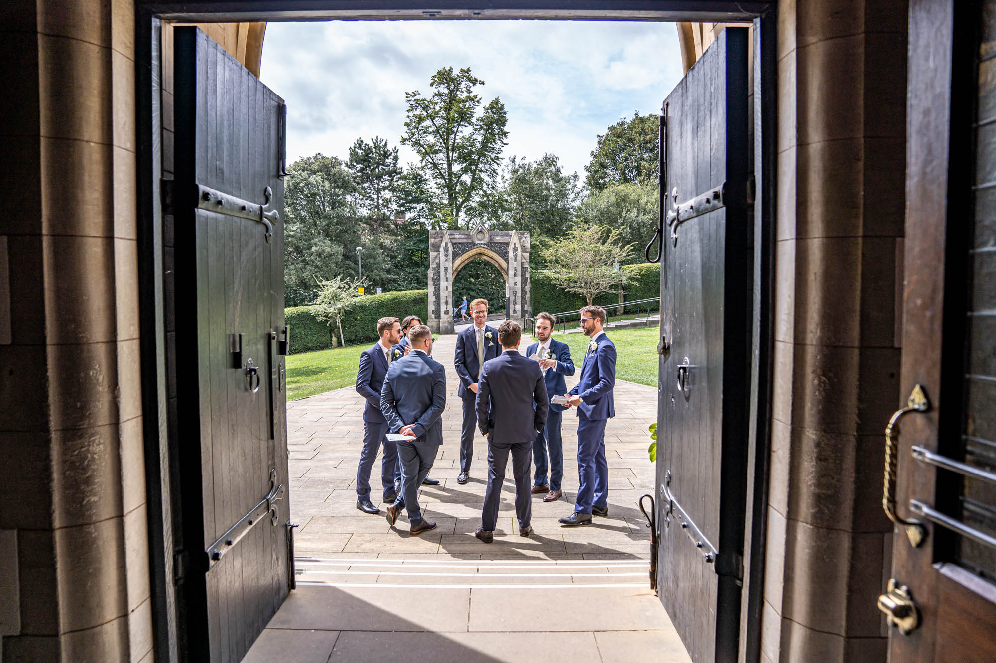 Groomsmen standing in church gardens.