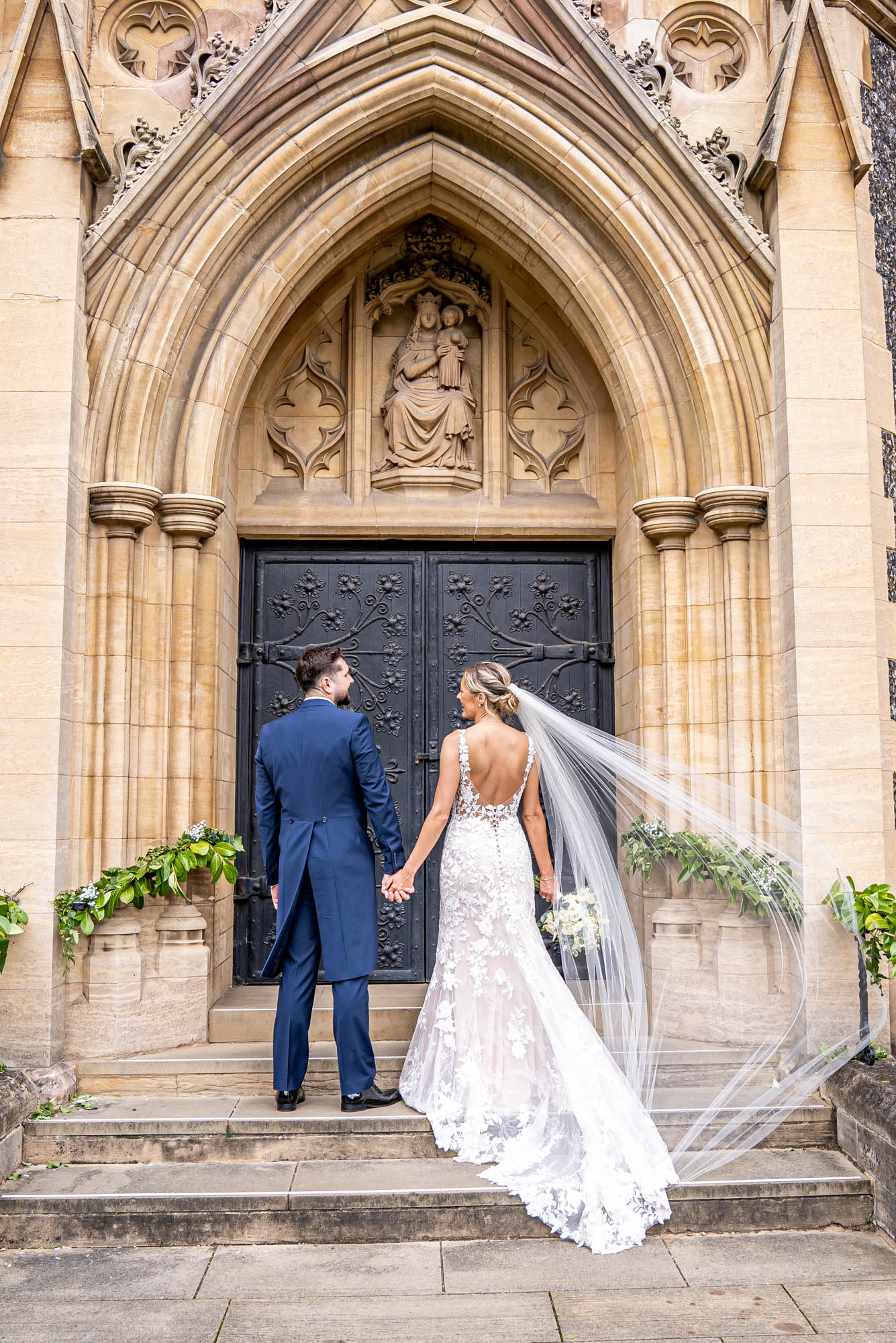 Bride and groom stand together on church steps .