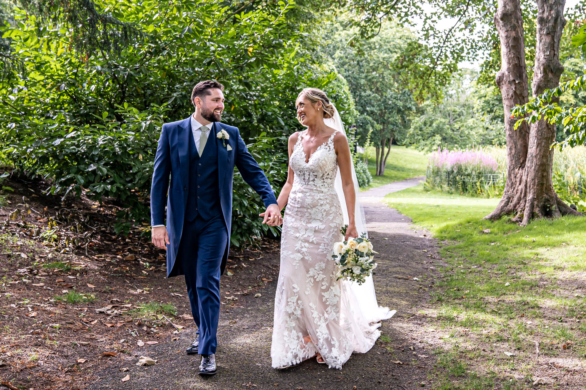 Newlyweds walk together holding hands.