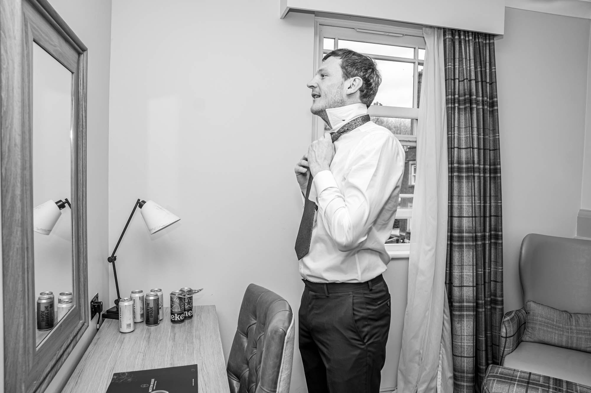Groom putting on his tie.