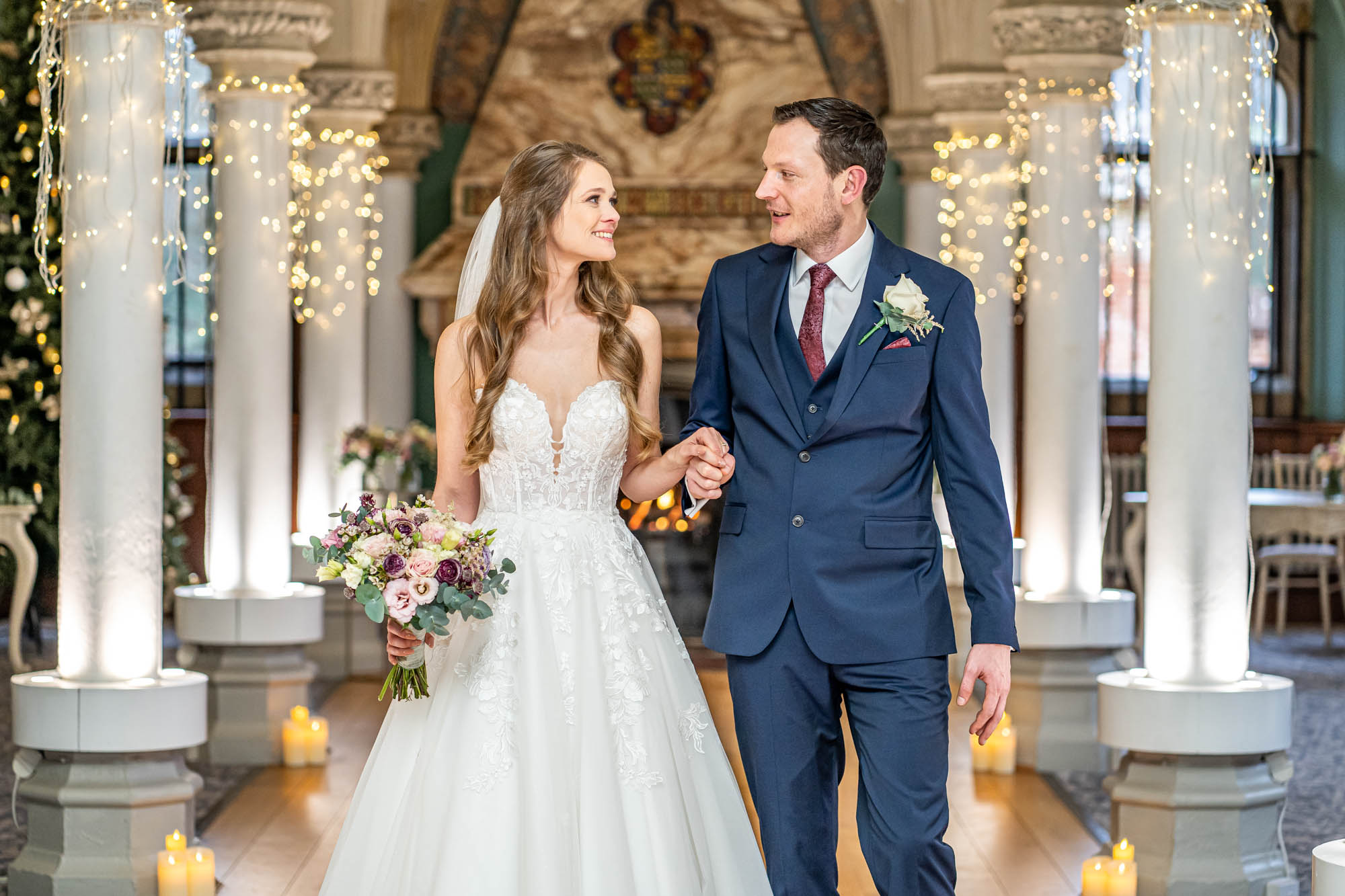 Newlyweds hold hands and walk together down the aisle of the Old Library at Wotton House.