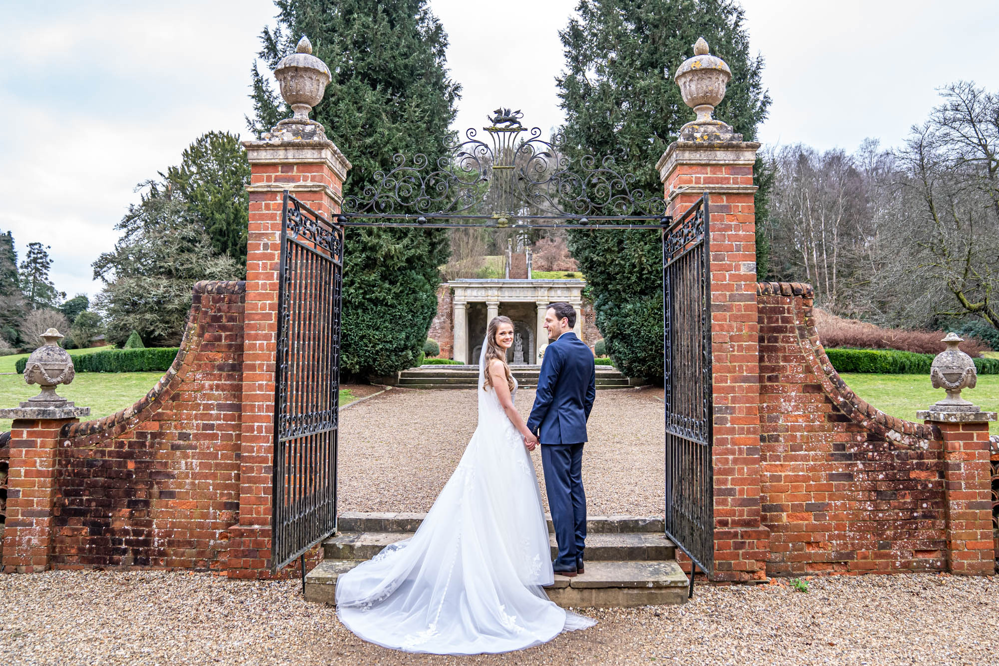 Newlyweds standing by gates in the grounds of Wotton House.
