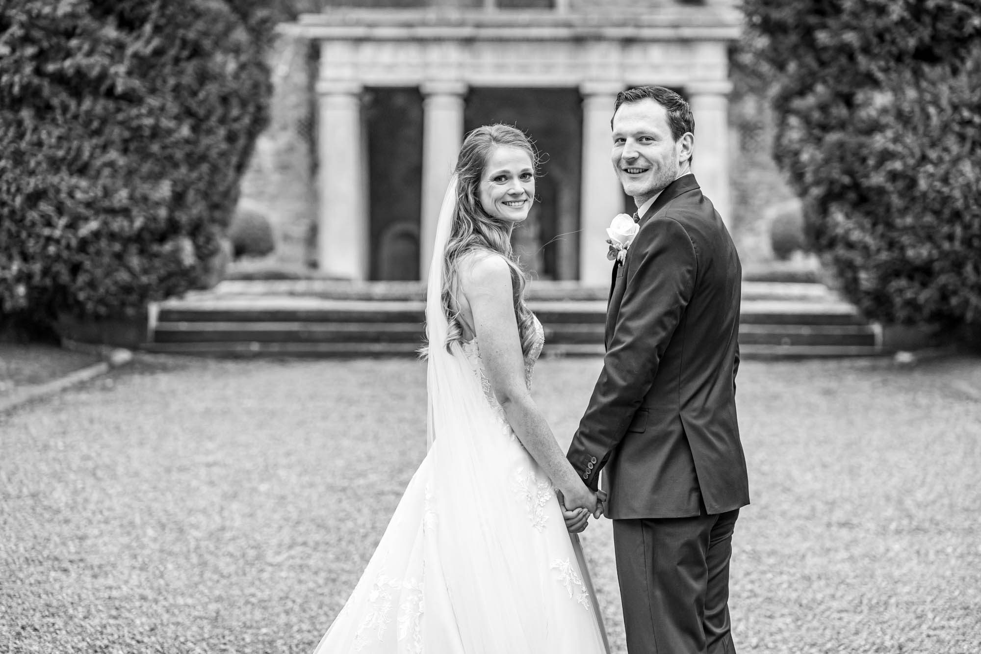Groom and bride stand together in the gardens.
